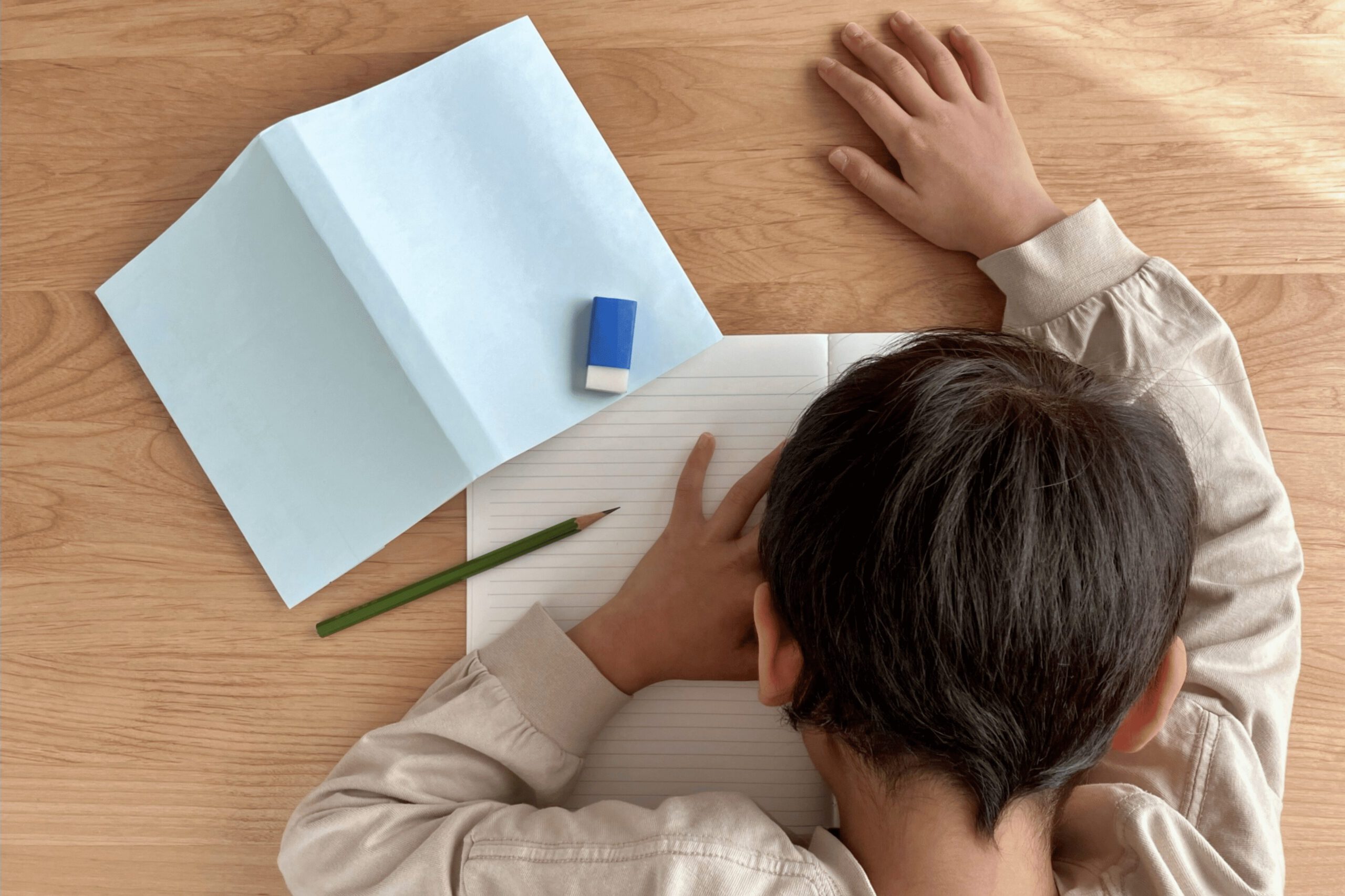 勉強に疲れて机に伏す小学生男子